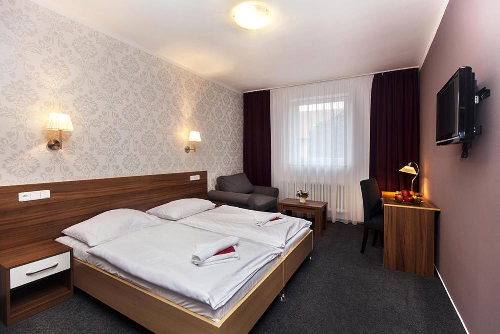 a hotel room with a bed and a television at Arkada Hotel in Bučovice
