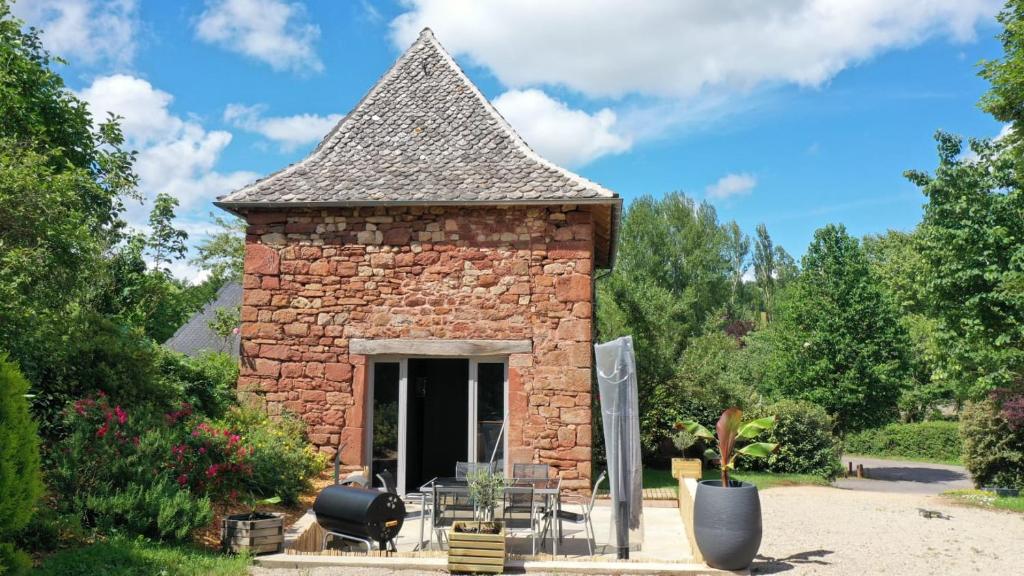 un petit bâtiment en briques avec un toit dans l'établissement Le moulin des vignes, à Clairvaux-dʼAveyron