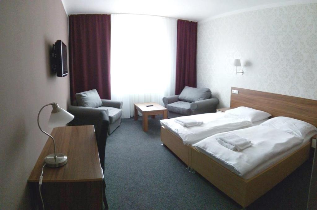 a hotel room with a bed and a chair at Arkada Hotel in Bučovice