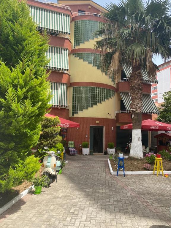 a building with a palm tree in front of it at Hotel Durres Vila 53 in Durrës