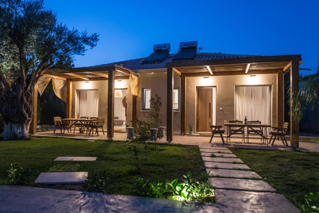 une maison avec une terrasse et des tables de pique-nique la nuit dans l'établissement Averta Rondo, à Leucade