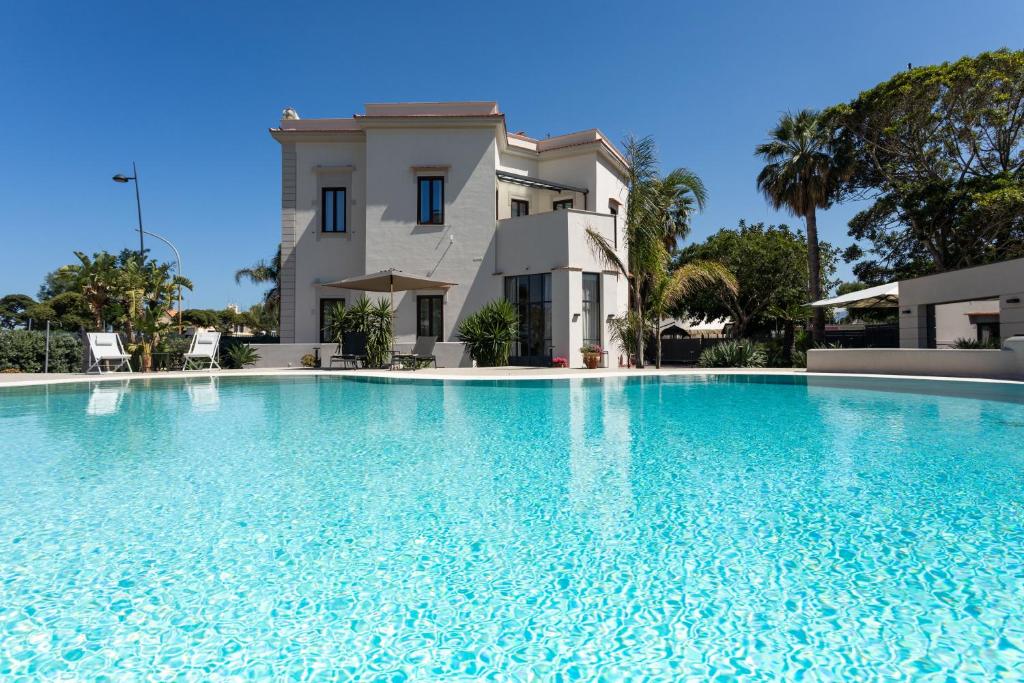 a large swimming pool in front of a house at Villa Masetta - Luxury Suites in Mondello