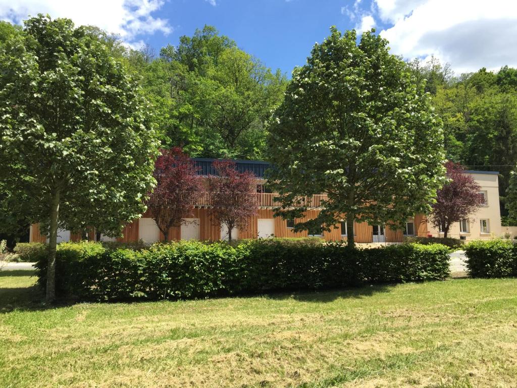 a building with trees in front of a yard at Logis Hôtel Les TILLEULS in Bruère-Allichamps