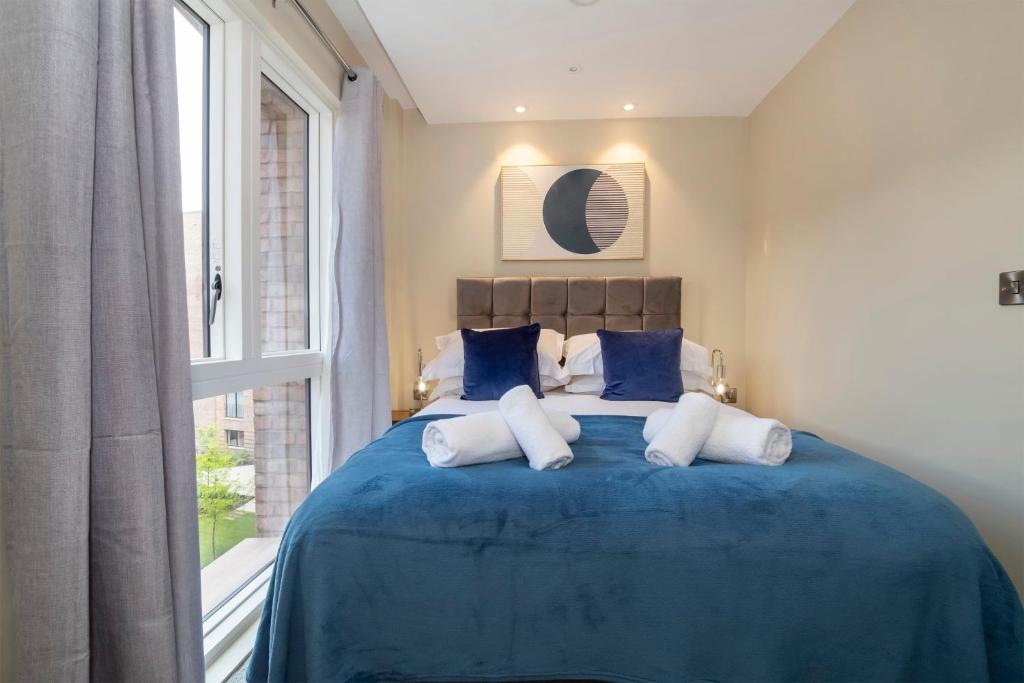 een slaapkamer met een blauw bed met kussens en een raam bij Hudson Quarter Luxury Apartments in York