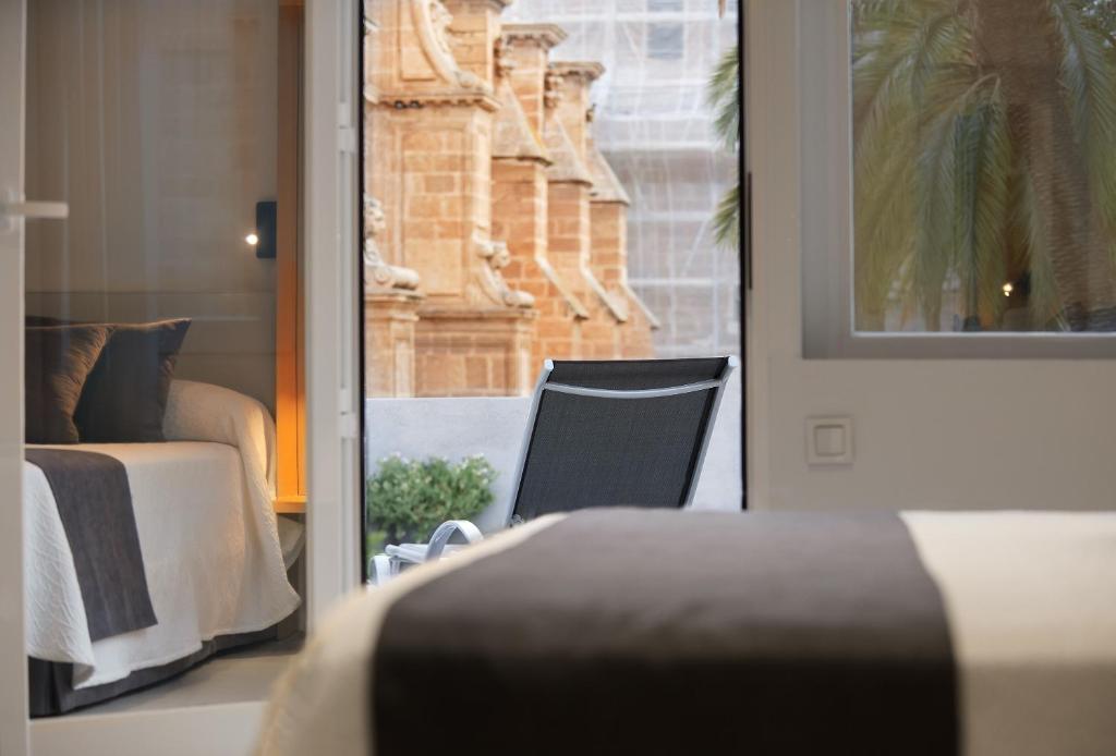 a bedroom with a bed and a chair and a window at Catedral Almería in Almería