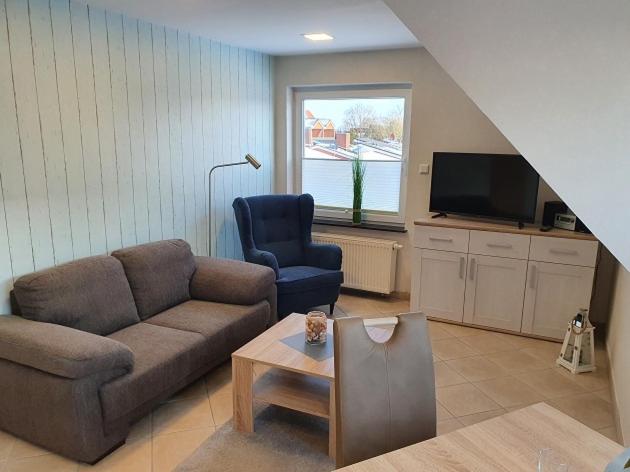 ein Wohnzimmer mit einem Sofa und einem Stuhl in der Unterkunft Apartmenthaus Robbe Luv in Neuharlingersiel