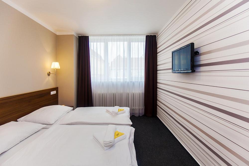 a hotel room with two beds and a flat screen tv at Arkada Hotel in Bučovice