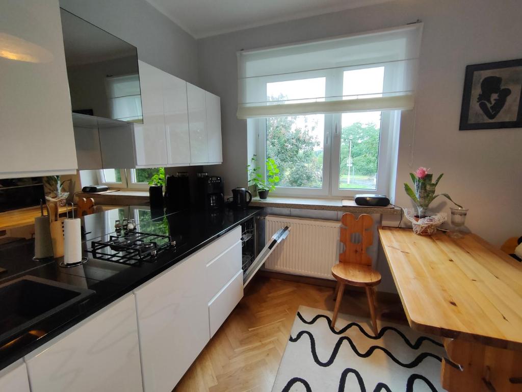 cocina con armarios blancos y suelo de madera en Apartamenty, dom przy Parku w centrum Zamościa en Zamość
