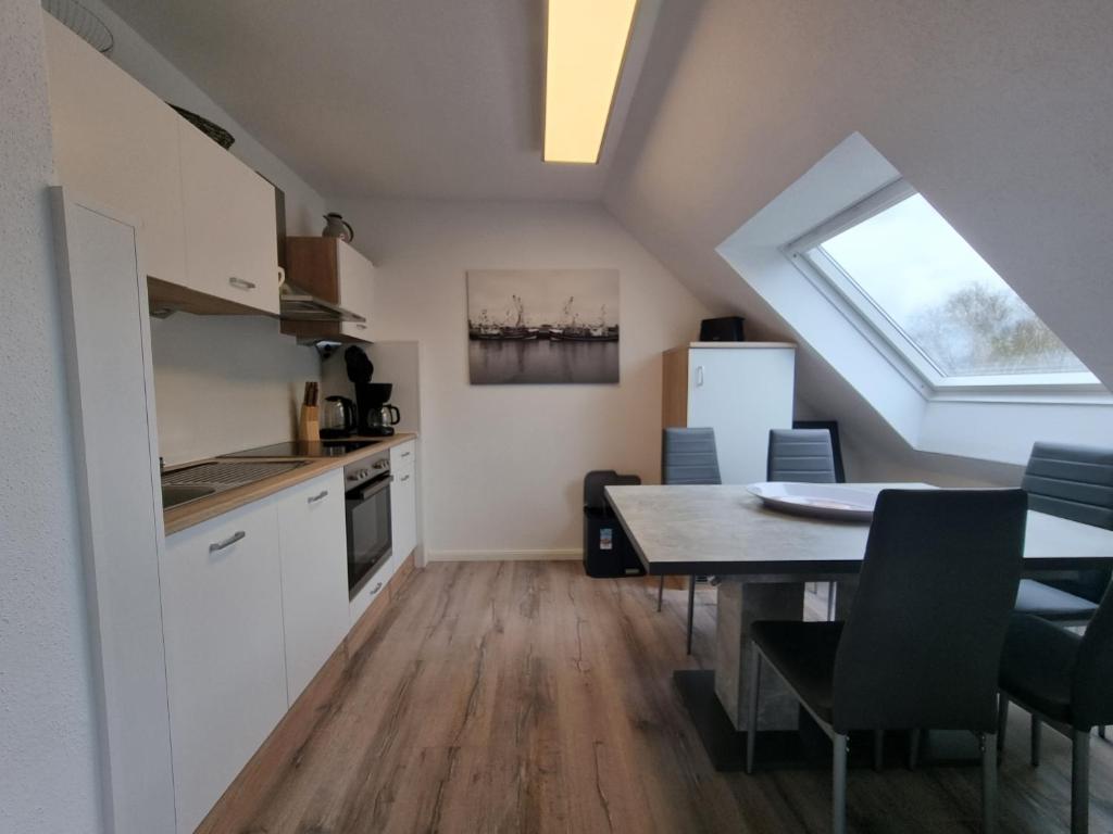 a kitchen and dining room with a table and a window at Ferienwohnung Nordwind in Neßmersiel