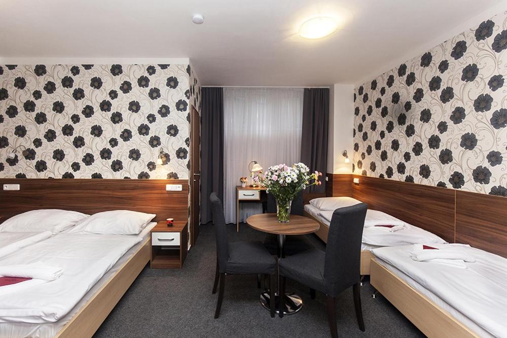 a hotel room with two beds and a table with flowers at Arkada Hotel in Bučovice