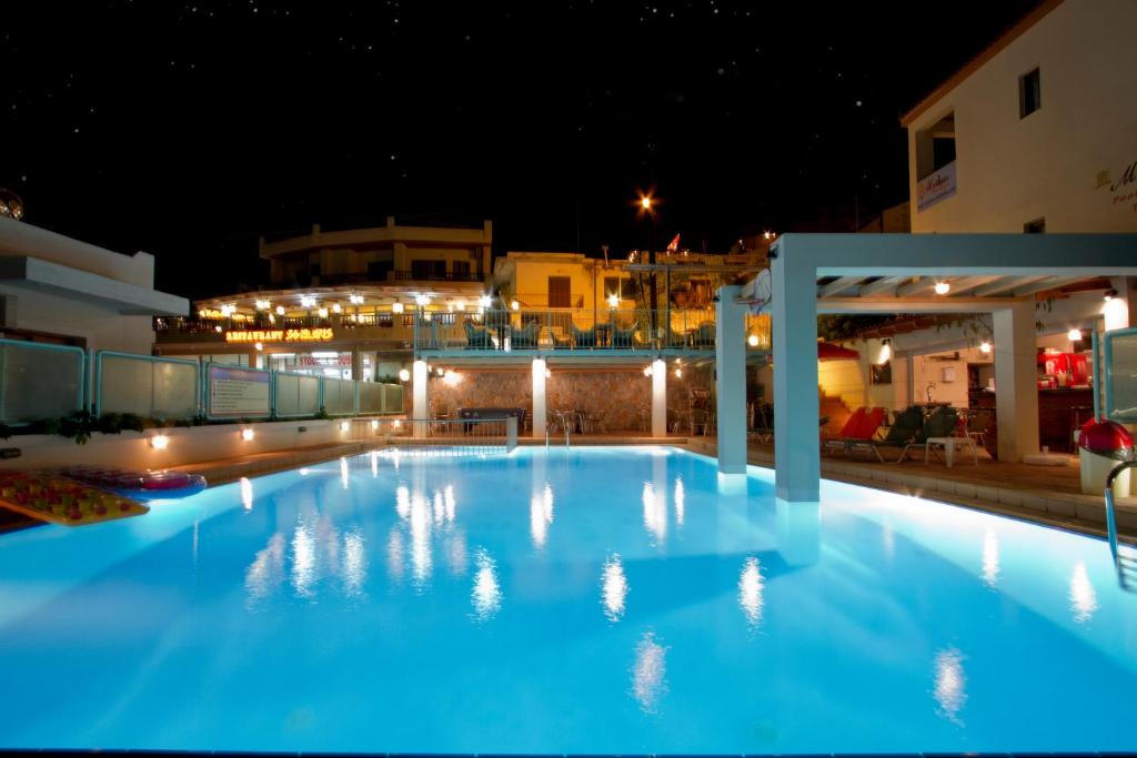 a large blue swimming pool at night at SHINE VERANDA PRIVE APTS 7PERSONS in Plataniás