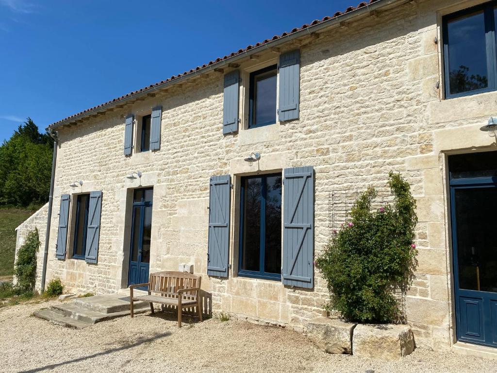 un bâtiment en briques avec un banc devant lui dans l'établissement Château des Loups - Les Pommiers, à Échiré