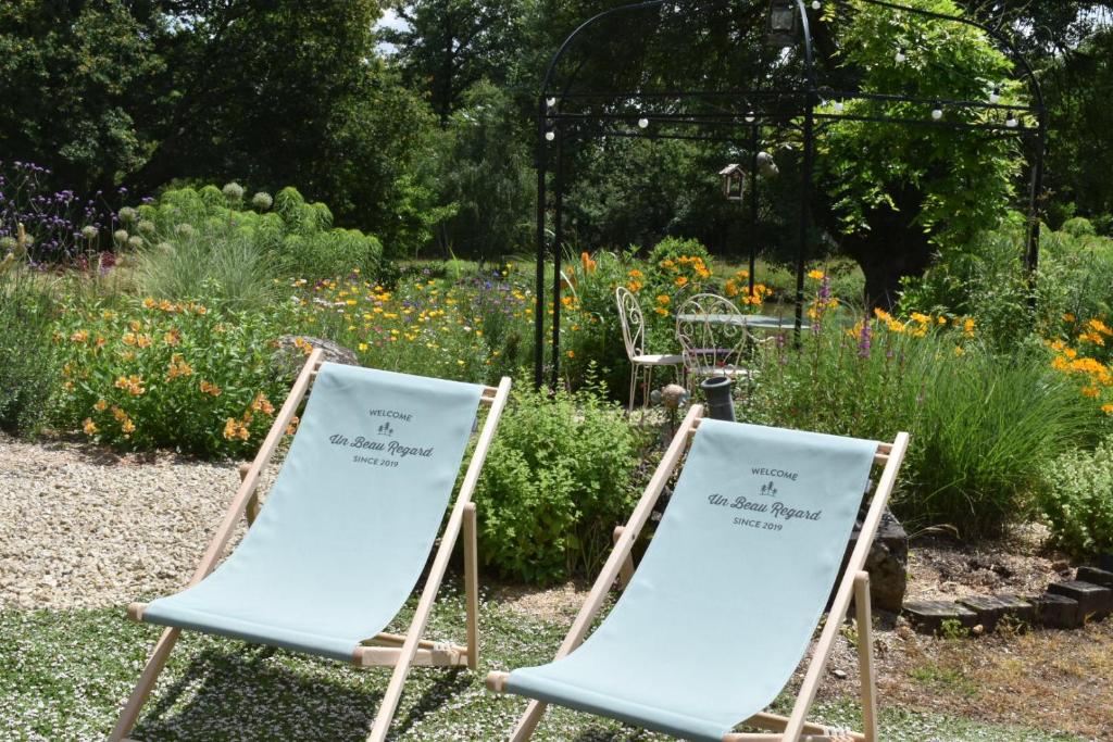 2 chaises assises dans un jardin fleuri dans l'établissement Un Beau Regard sur la nature !, à Mauléon