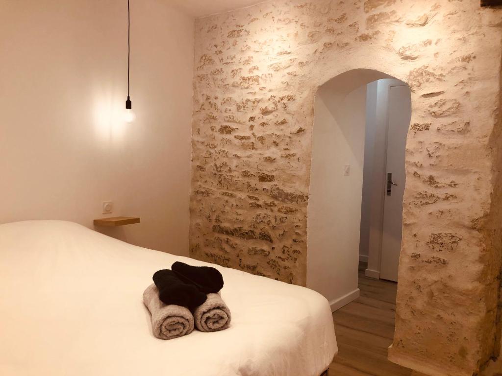 une chambre avec un lit et un mur en pierre dans l'établissement Le jungle charmant appartement avec extérieur, à Nîmes