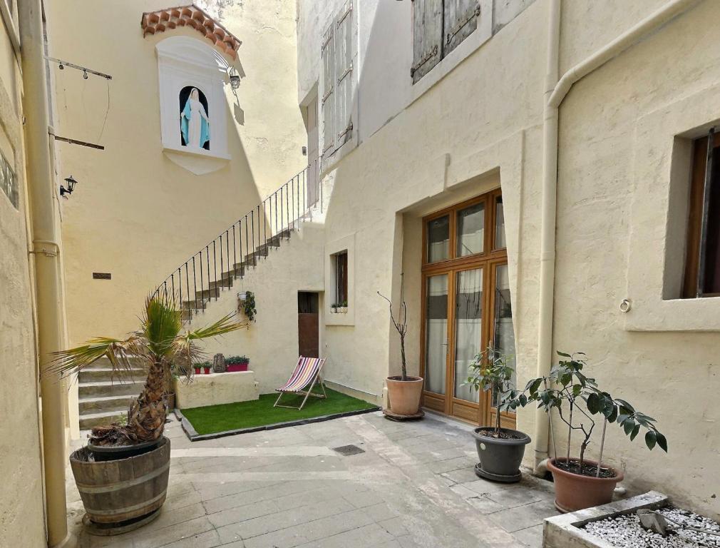 a courtyard of a building with a chair and potted plants at Des appartements au calme dans un immeuble historique in Béziers