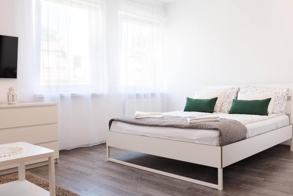 Dormitorio blanco con cama con almohadas verdes en Marcowy, en Sopot