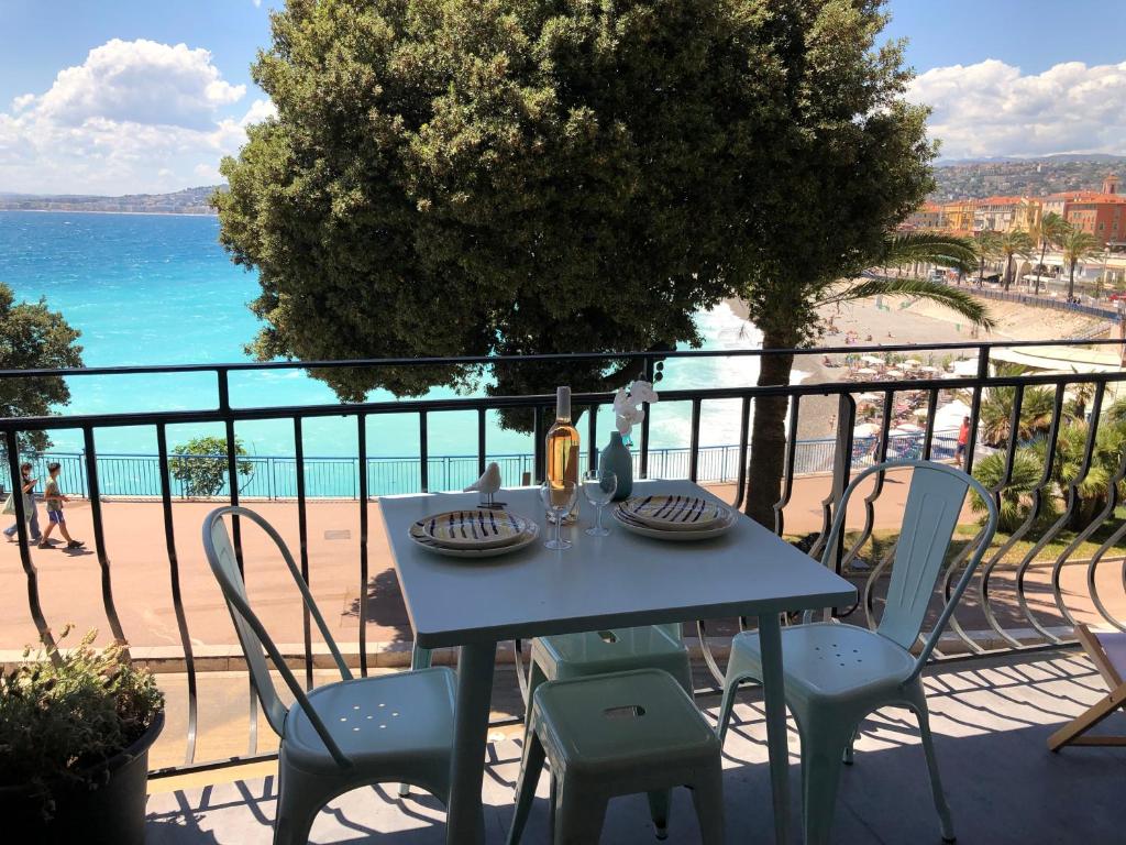 a table and chairs on a balcony with a view of the beach at I love Nice - FACE MER, DESIGN, TERRASSE, ASC, WIFI, CLIM in Nice