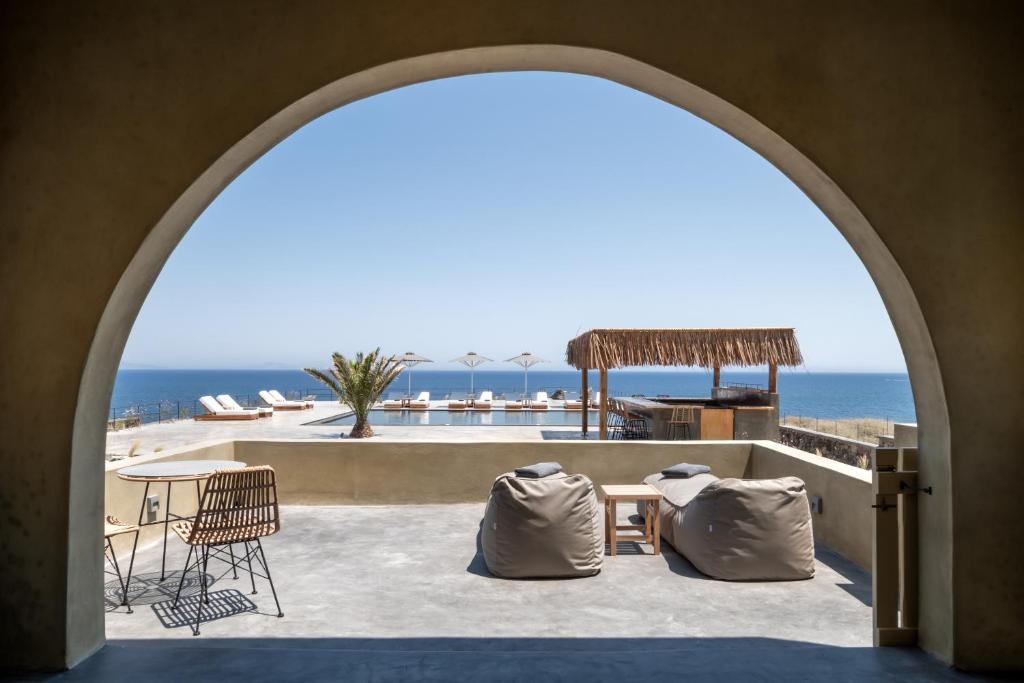 an archway over a patio with the ocean in the background at Colombos Beachfront in Foinikiá