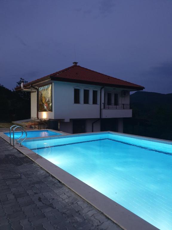 a large blue swimming pool in front of a house at Бадевски рай- къща София in Veliko Tŭrnovo