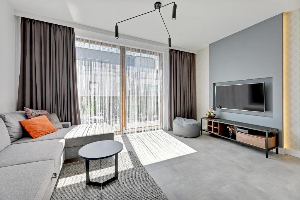 a living room with a couch and a tv at Dom & House - Apartments Nadmorski Park in Gdańsk