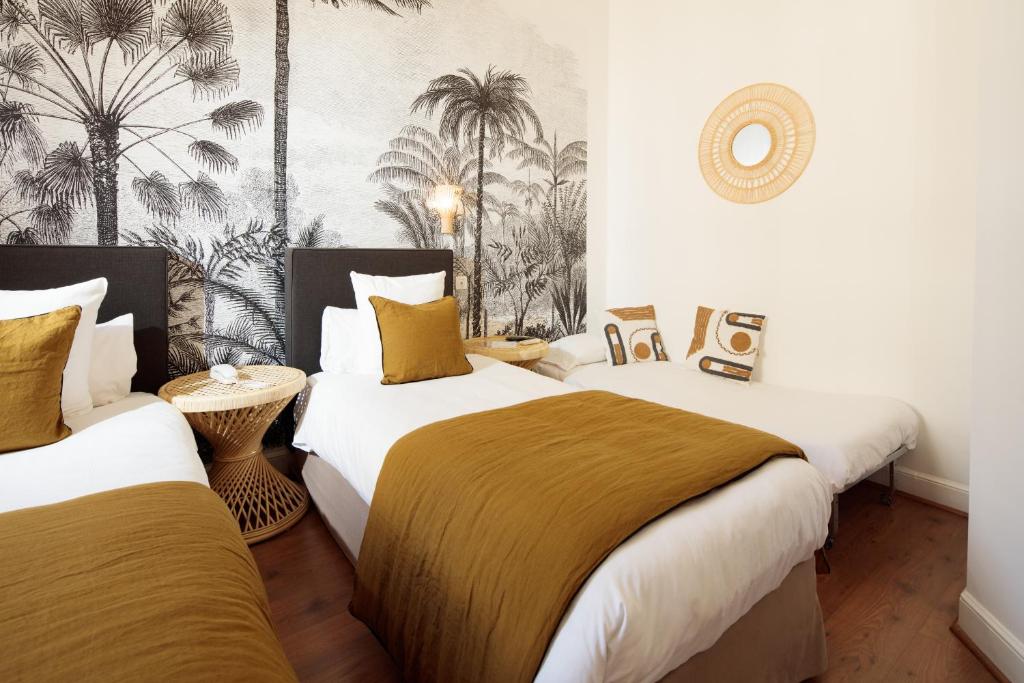 - 2 lits dans une chambre avec des palmiers sur le mur dans l'établissement Hôtel La Résidence, à Narbonne