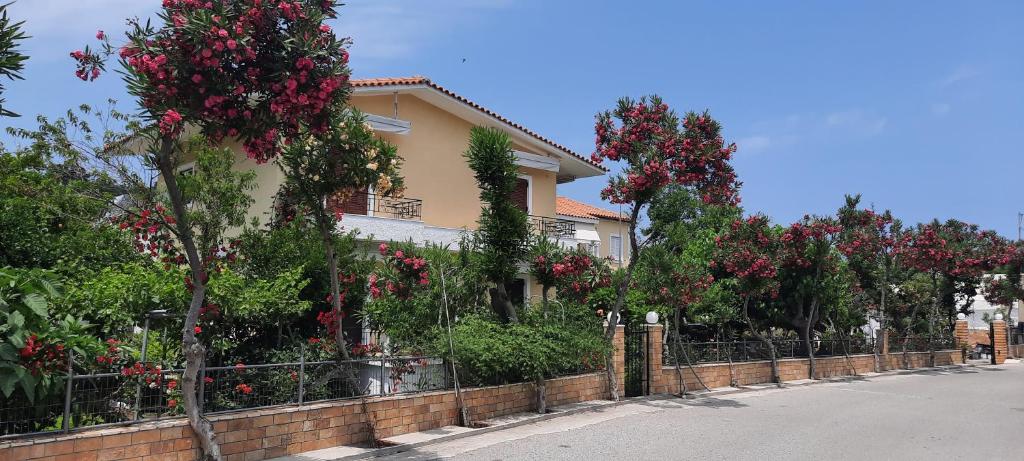 una casa con flores rojas delante de una valla en koula's apartments, en Vasilika