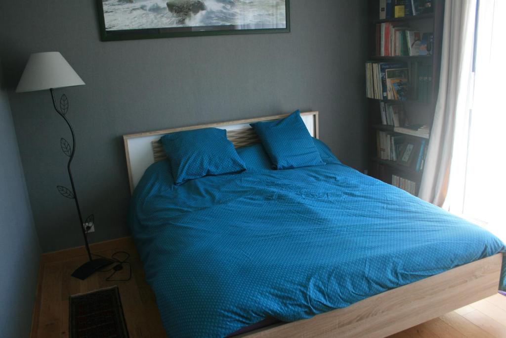 拉莫爾海灘的住宿－Chambre avec accès piscine intérieure，卧室里一张带蓝色床单和灯的床