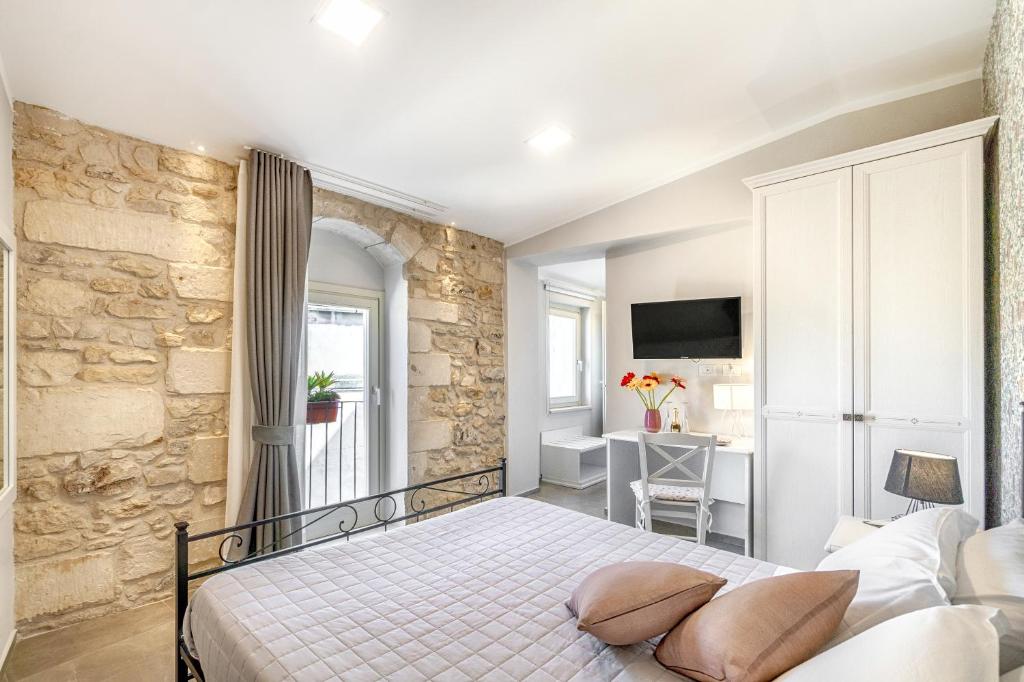 1 dormitorio con cama y pared de piedra en B&B Via Barocca, en Ragusa