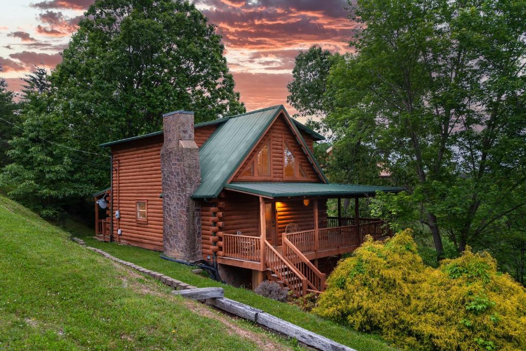 een blokhut met een veranda en een groen dak bij Mountain Serenity Cabin in Sevierville