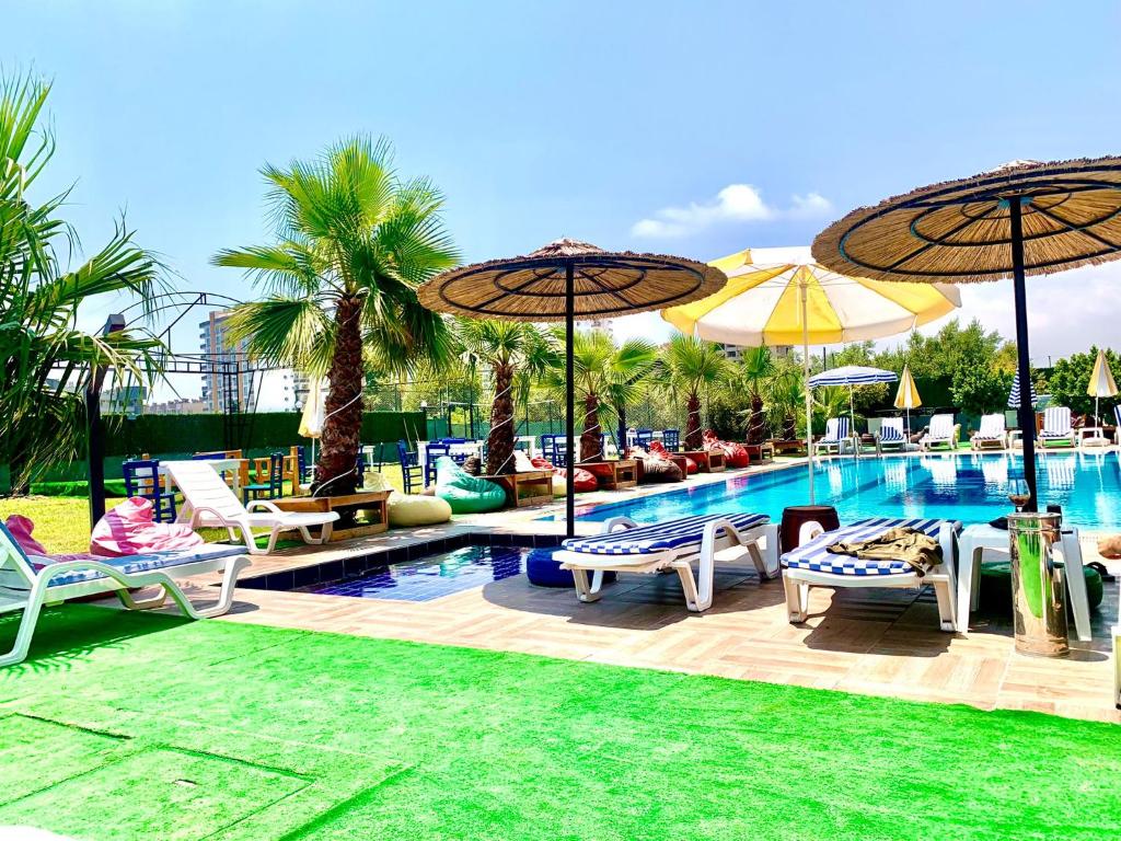 una piscina con sillas y sombrillas junto a un complejo en Vm Resort Otel Mersin, en Mersin