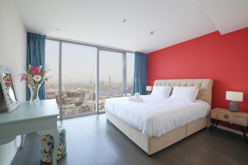 a bedroom with red walls and a white bed and a desk at D1 Tower - 2BR Apartment - Allsopp&Allsopp in Dubai