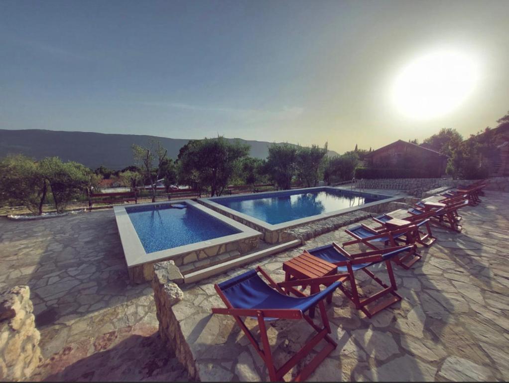 a pool with a bunch of lawn chairs and a group at Ethno Village Pajo in Herceg-Novi