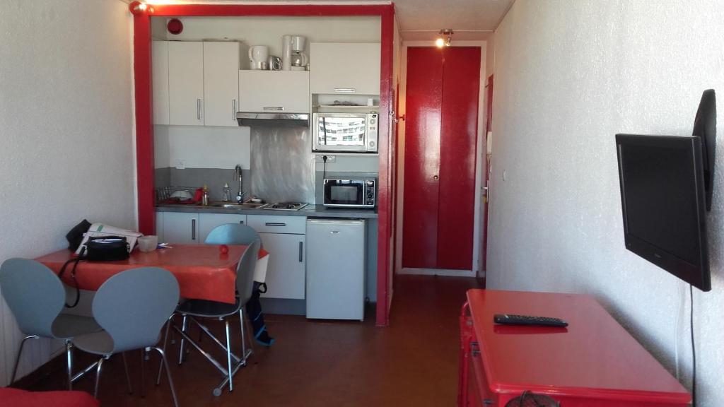 a small kitchen with a red table and a red door at Le Callisto 2 in Mauguio