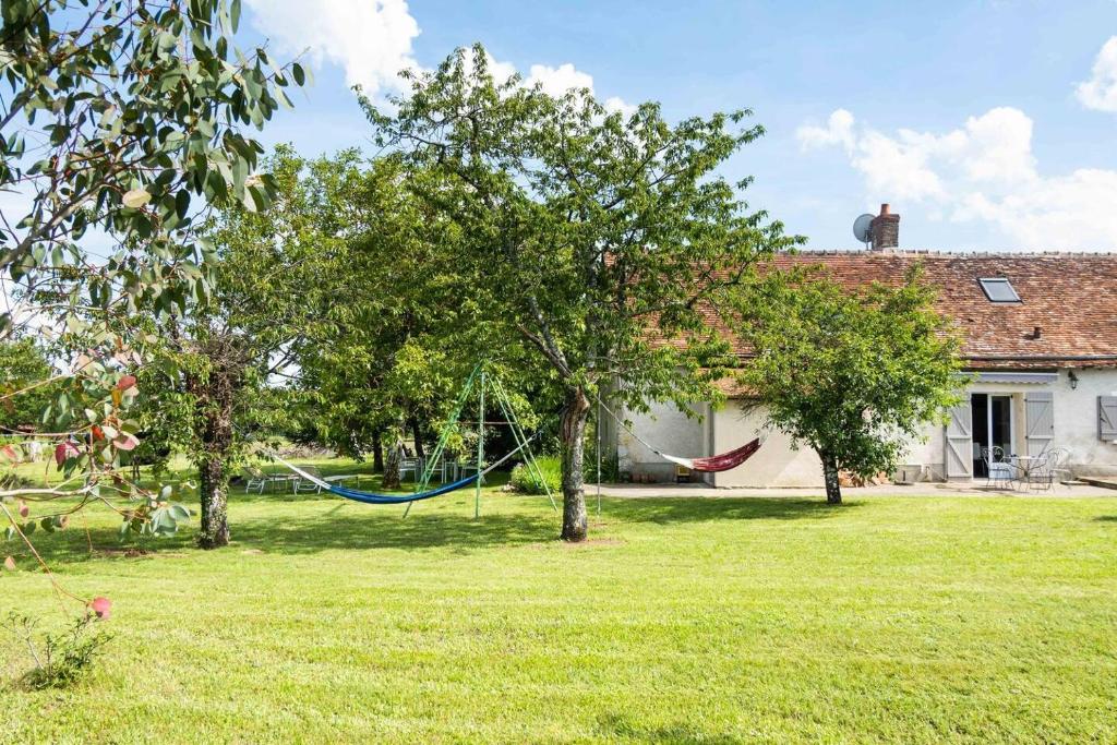 une cour avec deux arbres et un hamac en face d'une maison dans l'établissement Beautiful 4-Bed House in Rilly-sur-Loire, à Rilly-sur-Loire