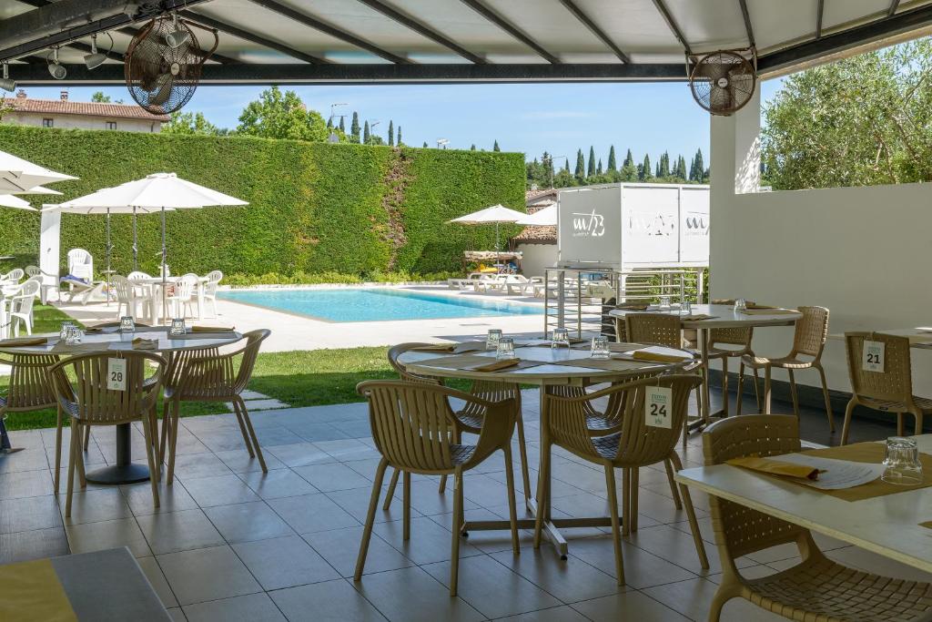 ソルフェリーノにあるAgriturismo La Torretta da Valentinaのテーブルと椅子のあるレストラン、プールを提供しています。