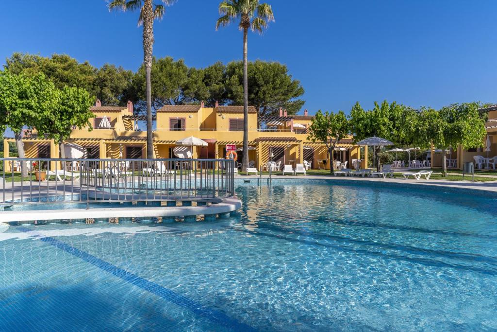 a swimming pool at a resort with palm trees at Apartamentos Ses Anneres in Cala en Blanes