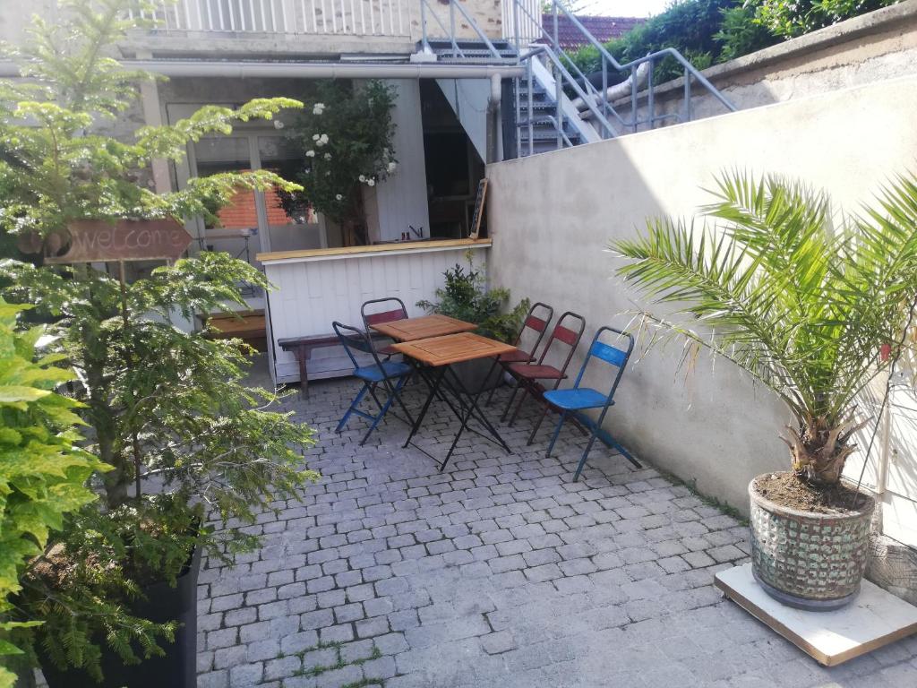 een patio met een houten tafel en stoelen en een plant bij Gites Le Roosevelt - Côte 204 in Château-Thierry