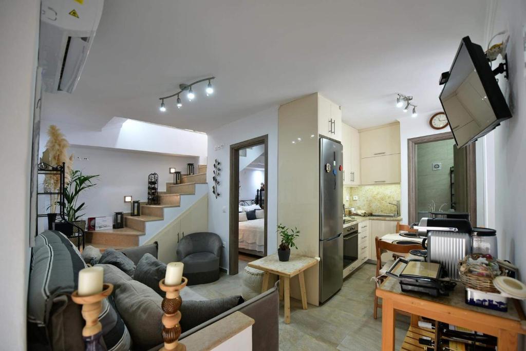 a living room with a couch and a kitchen with a staircase at Agate Hydra luxury apartment in Hydra