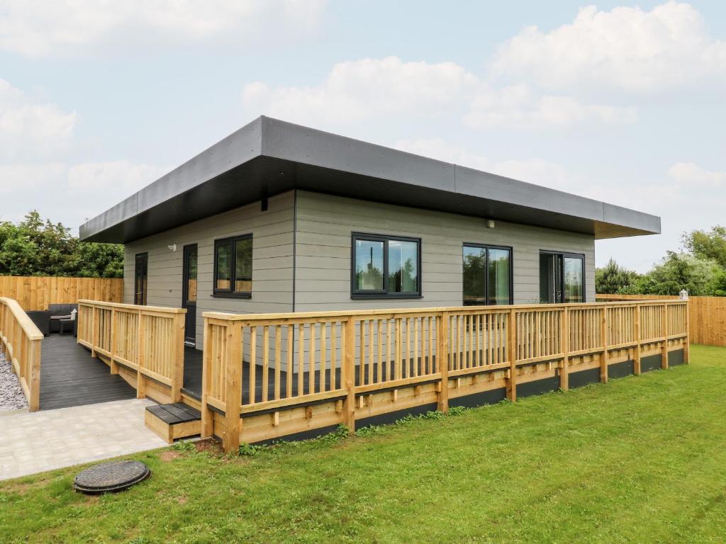 a modular home with a large wooden deck at Meadowbank Lodge in Brandesburton