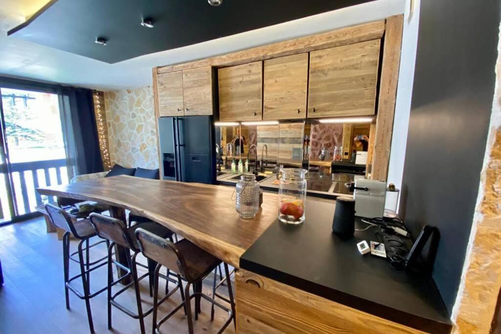 a kitchen with a large wooden island with bar chairs at Le Chappart de Valberg - en plein centre in Péone