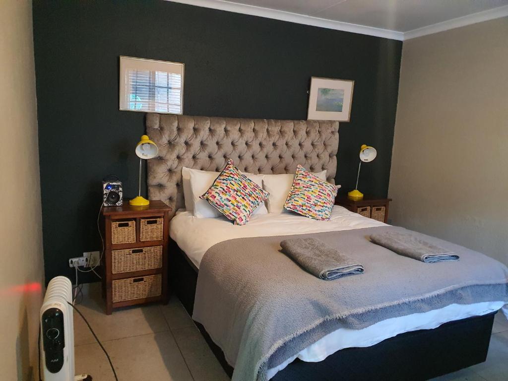 um quarto com uma cama grande e 2 almofadas em Happy colourful cottage em Joanesburgo