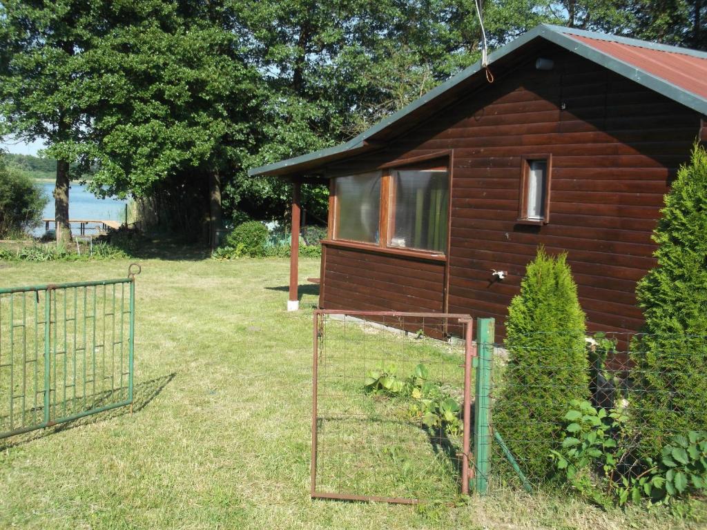 a small wooden house with a gate in the yard at Domek nad jeziorem -Mazury- Linia Brzegowa in Piotrowice