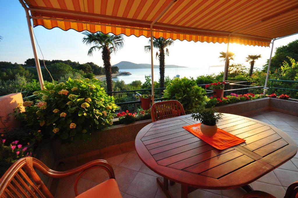 una mesa de madera en un patio con vistas al océano en TRI PALME, en Prvić Šepurine