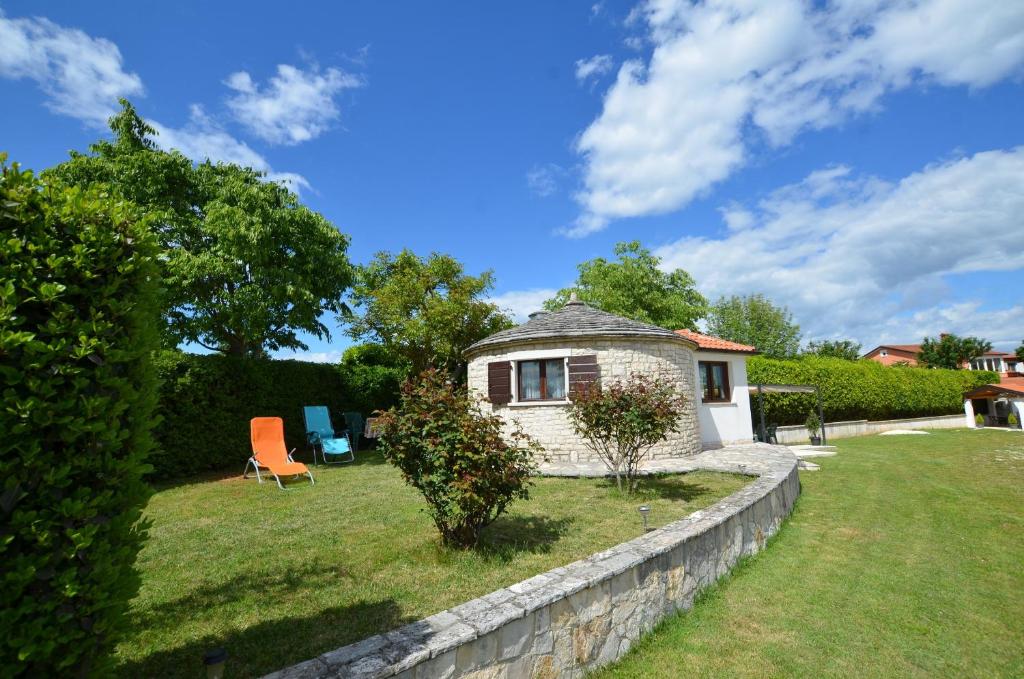een klein stenen huis met een stoel in een tuin bij Zminj Apartments in Žminj