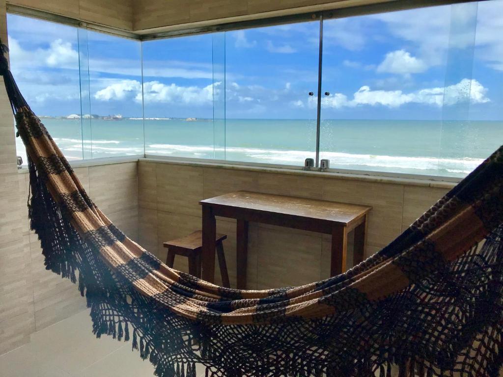 a hammock in a room with a view of the ocean at Edf. Maison Chateaubriand in Maceió