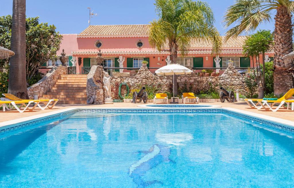 a swimming pool in front of a house with palm trees at L - Wellness Farm in Lagos