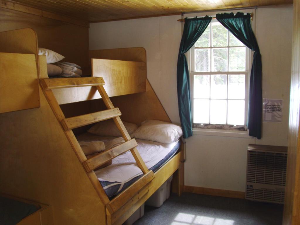 a small room with bunk beds and a window at HI Mosquito Creek Hostel in Lake Louise