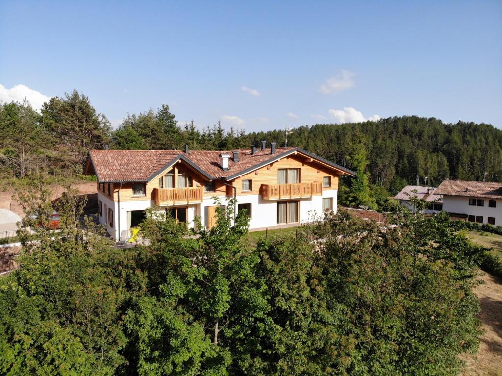 une maison au sommet d'une colline avec des arbres dans l'établissement Bioagritur La Casa dei Trajeri, à Fai della Paganella