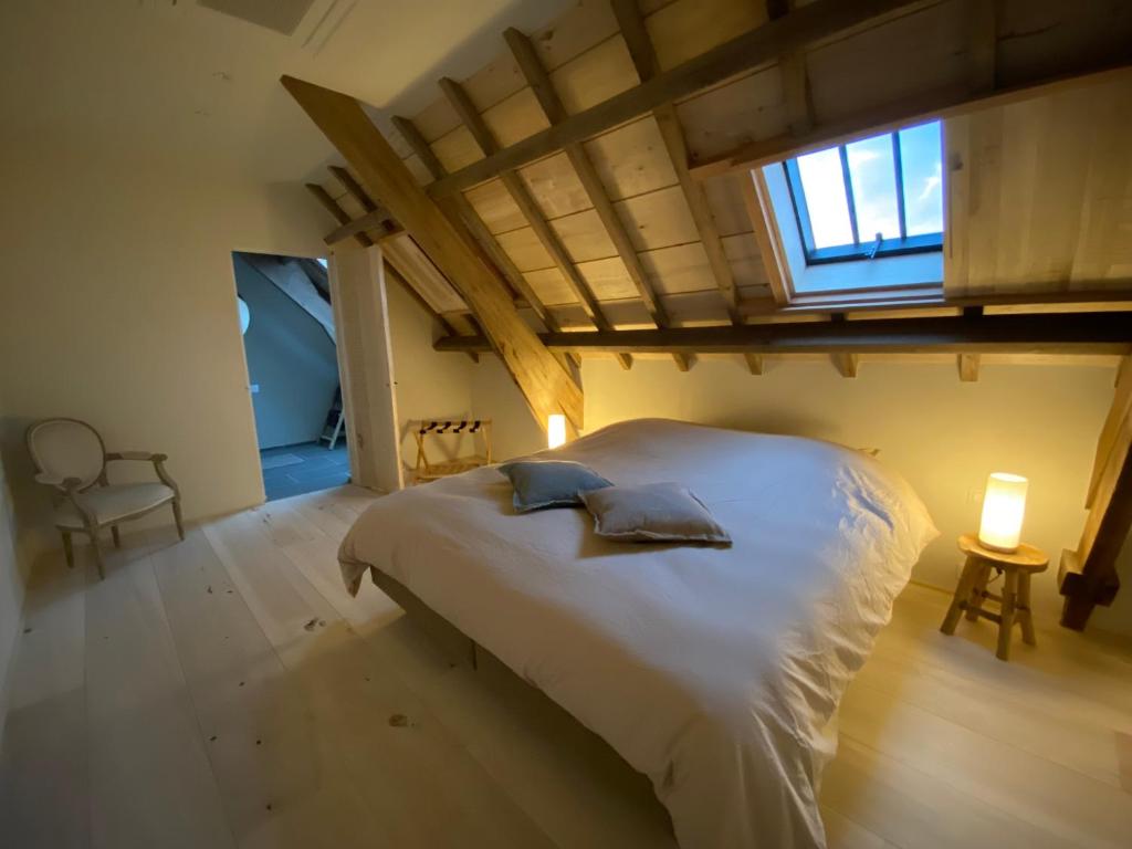 a bedroom with a large white bed with a window at Guesthouse Graaf Jan in Kaprijke