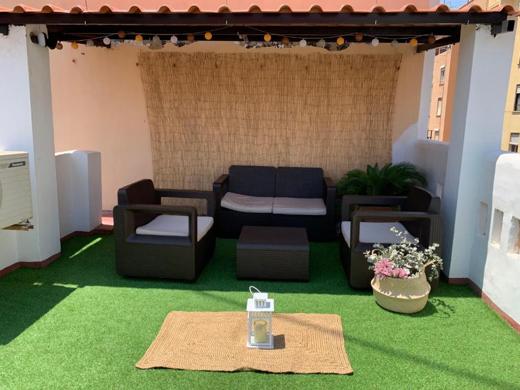 a patio with a couch and chairs on a green carpet at Habitación bien situada, cómoda y nueva in Valencia